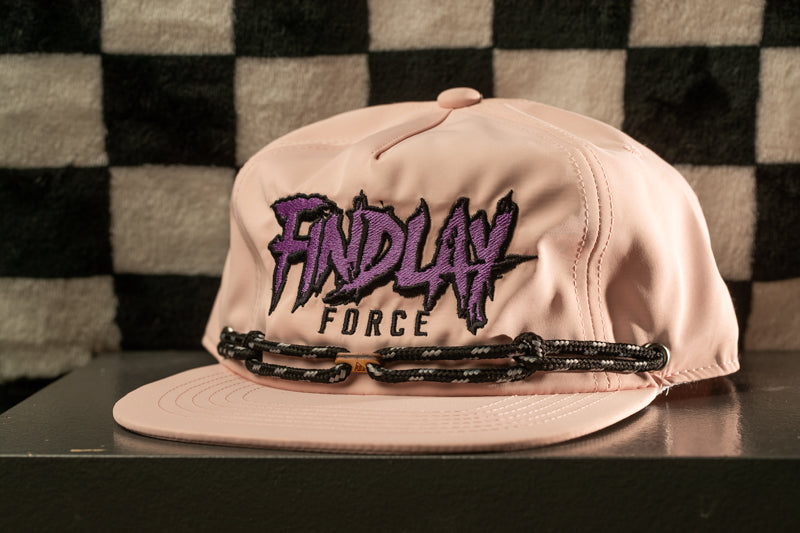 A pink baseball cap with the text "FINDlay Force" printed on it, sitting on a surface against a checkered background.