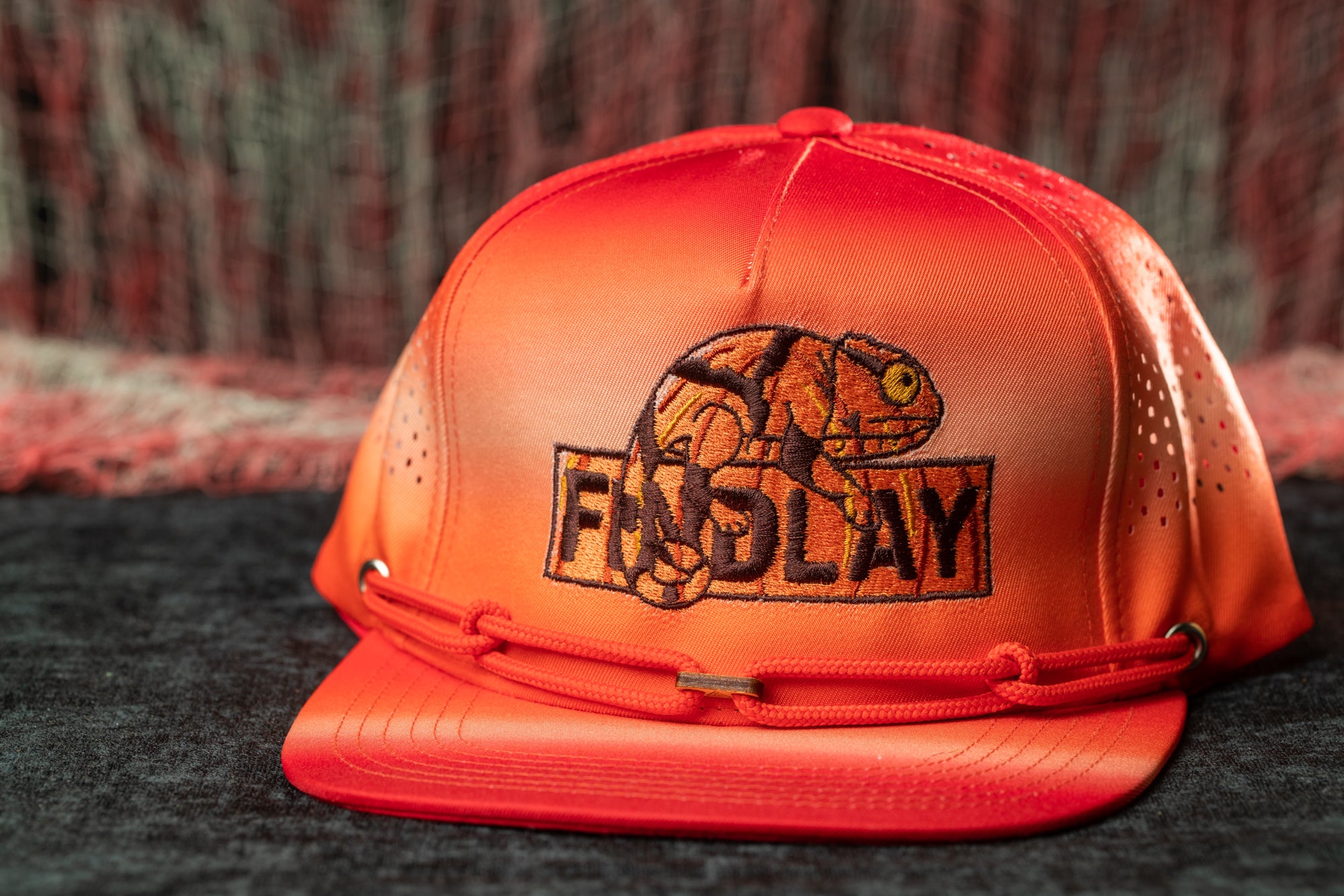 A red baseball cap with a graphic of a chameleon and the word "FINDlay" printed on it.