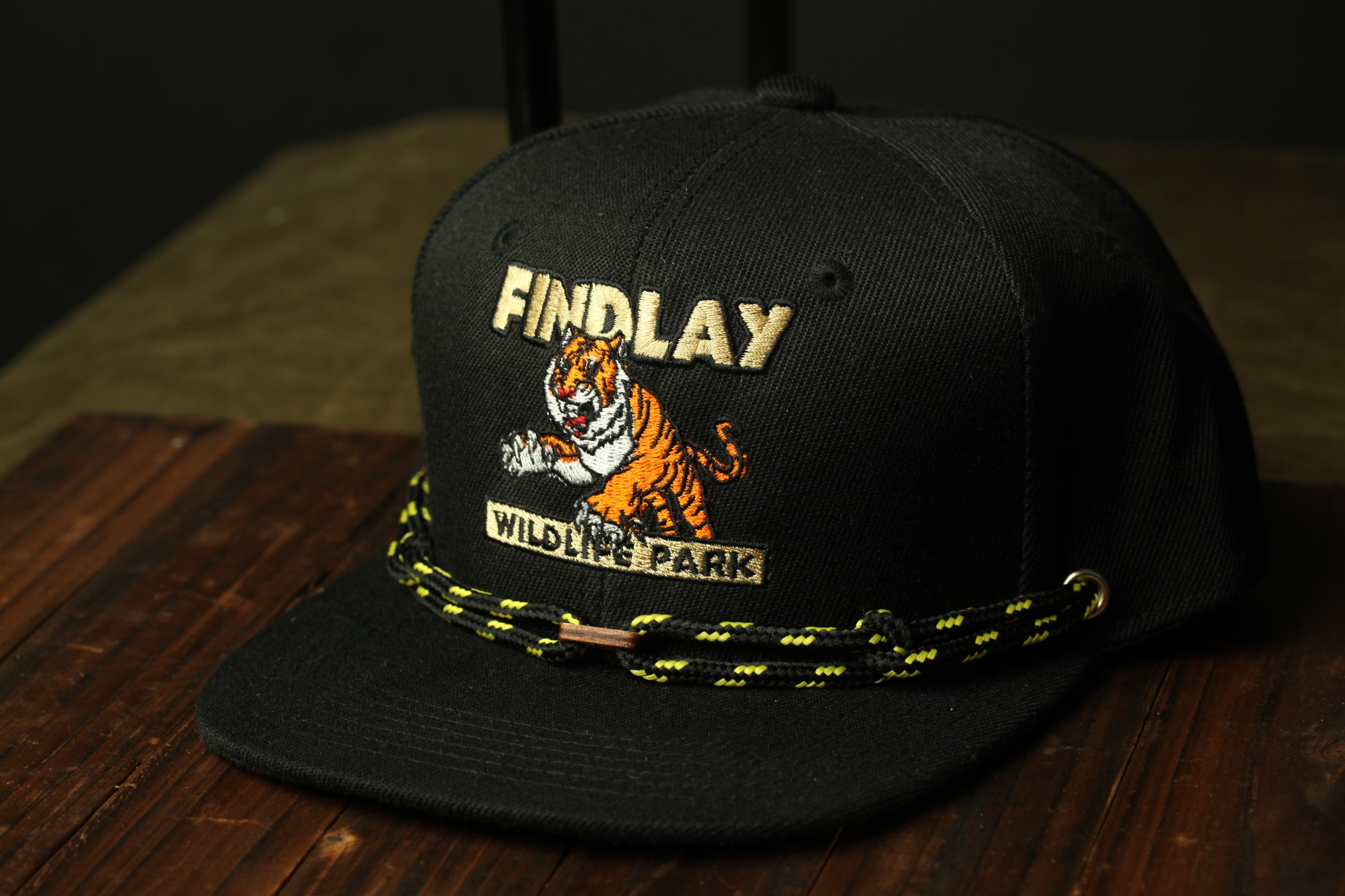 A black baseball cap with a tiger graphic and the text "FINDLAY WILD LIFE PARK" printed on it.