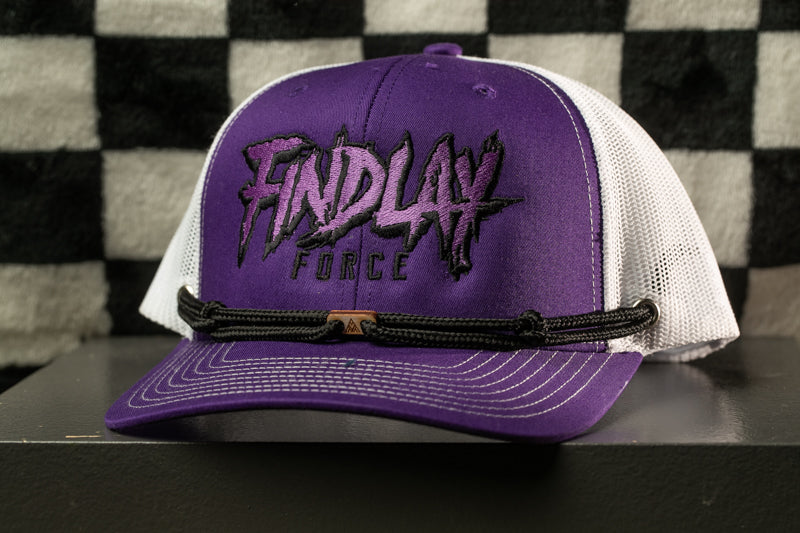A purple baseball cap with the text "FINDlay FORCE" printed on it, sitting on a black surface against a checkered background.