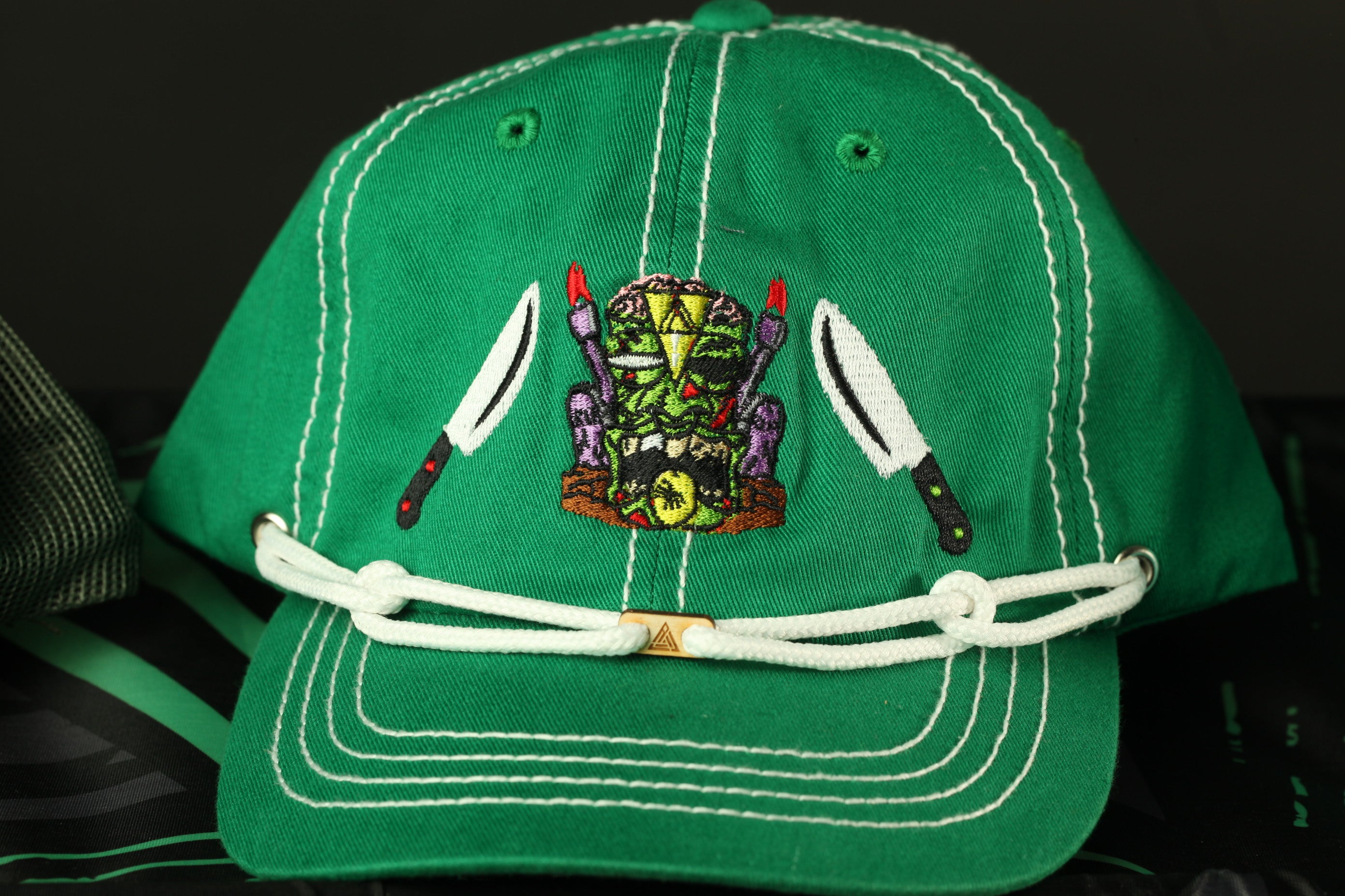 A green baseball cap with a white trim and a colorful design featuring a mask and a skull.