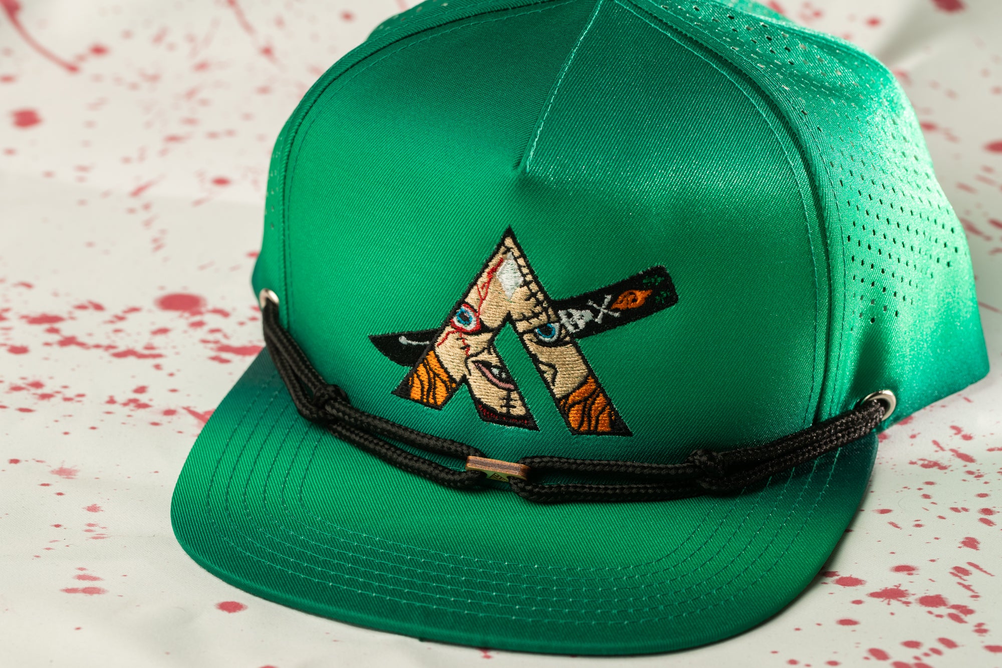 A green baseball cap with a unique embroidered design on the front.