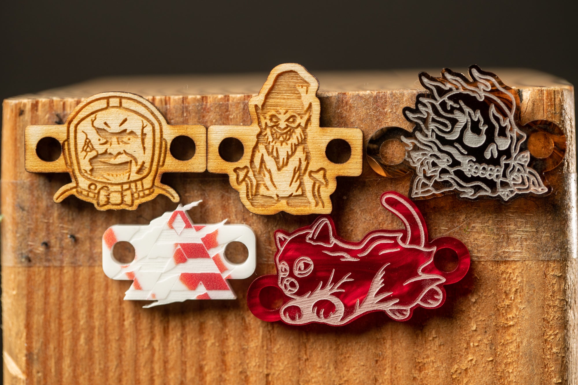 a collection of five wooden objects, including a skull, a cat, and other abstract designs, displayed on a wooden surface.