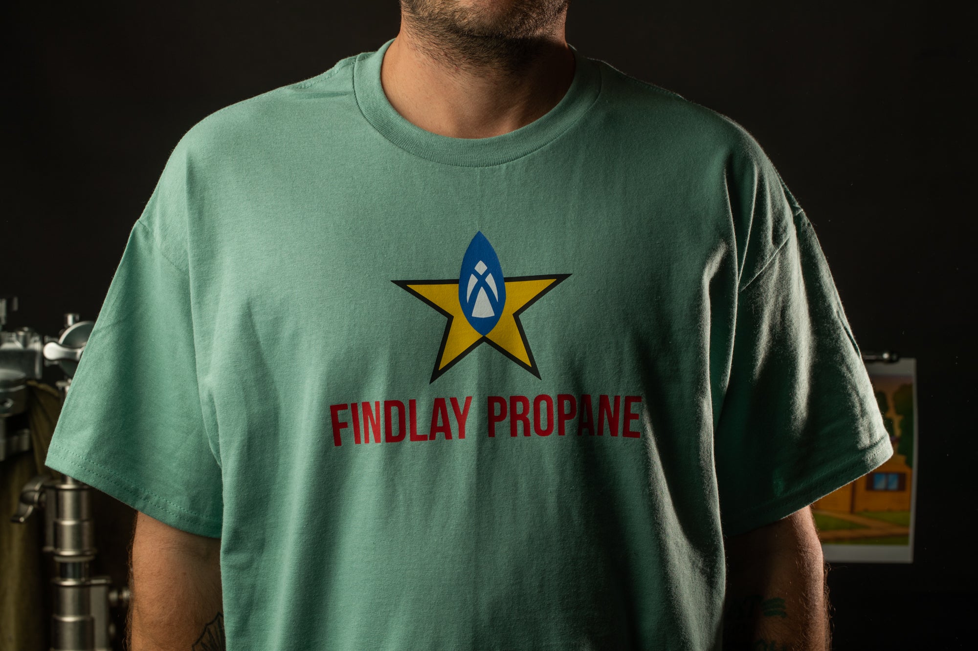 A person wearing a green t-shirt with a graphic design and text printed on it.