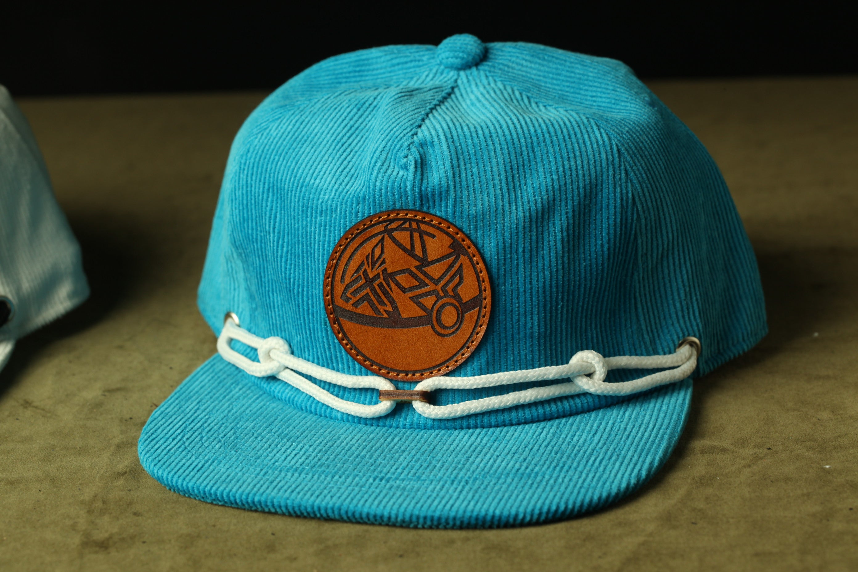 A blue baseball cap with a leather patch and white straps.