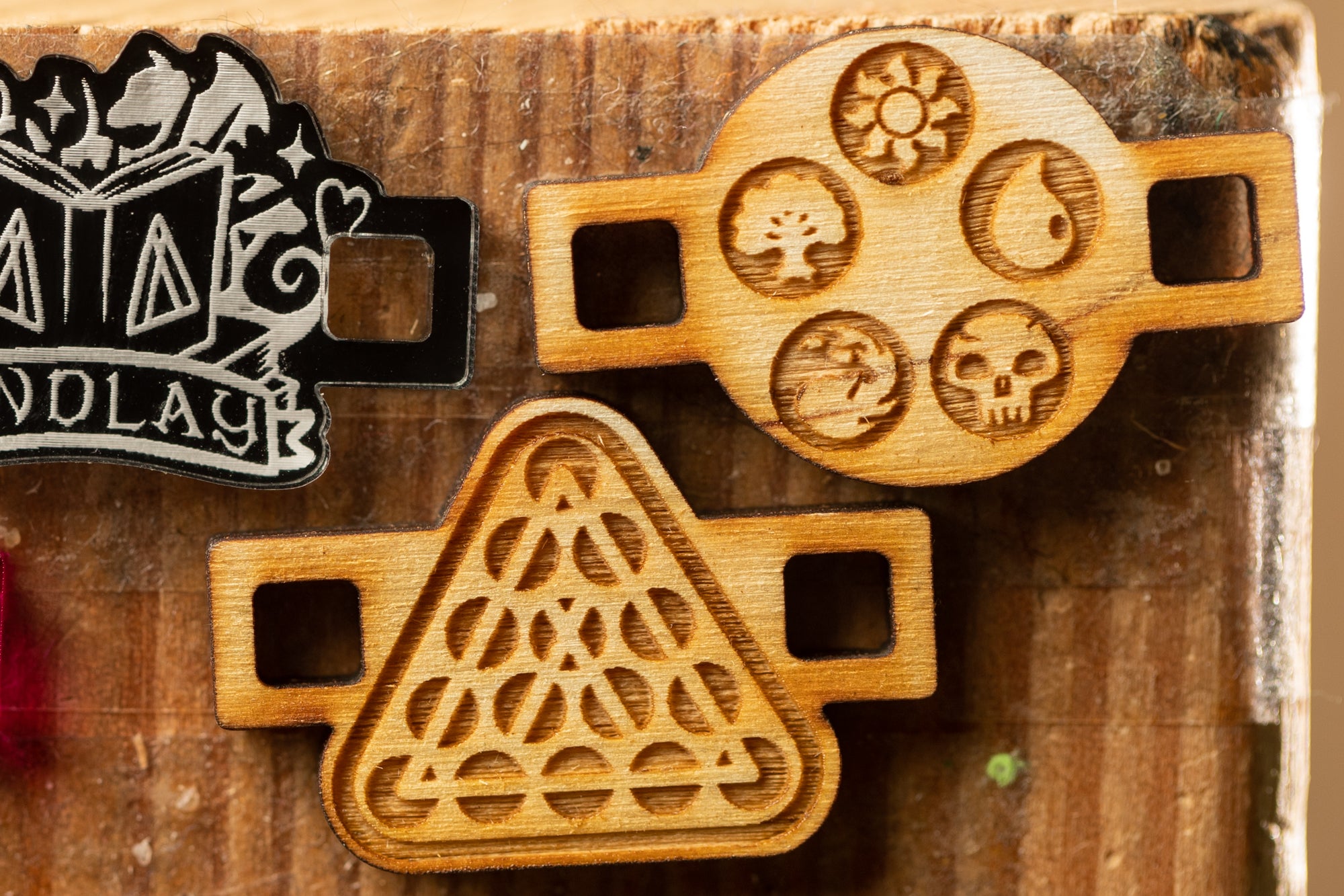 three wooden objects with intricate designs carved into them, displayed on a wooden surface.
