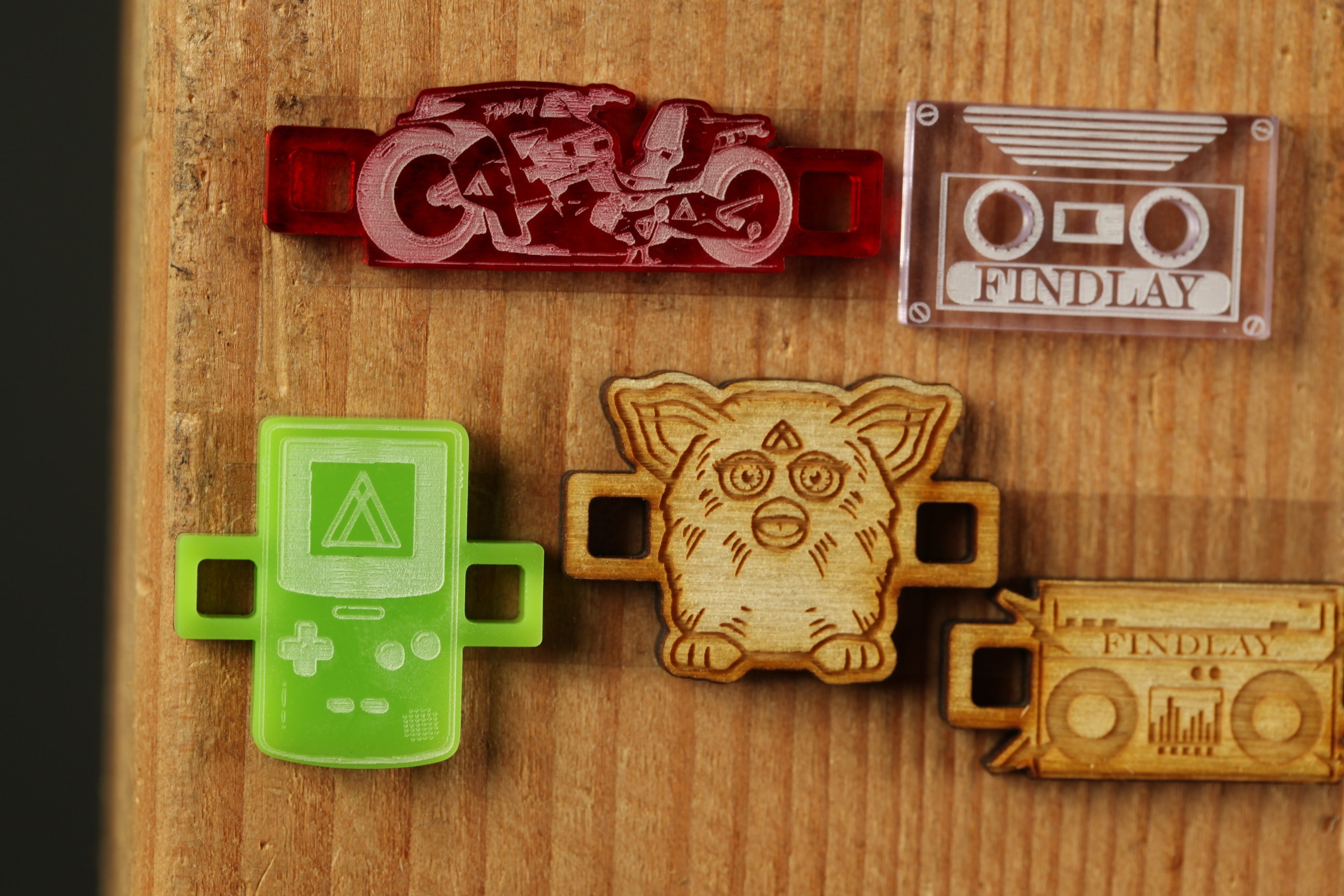 a collection of five different objects, including a green game controller, a red motorcycle, a white cassette tape, a wooden toy resembling a cat, and a wooden boombox.