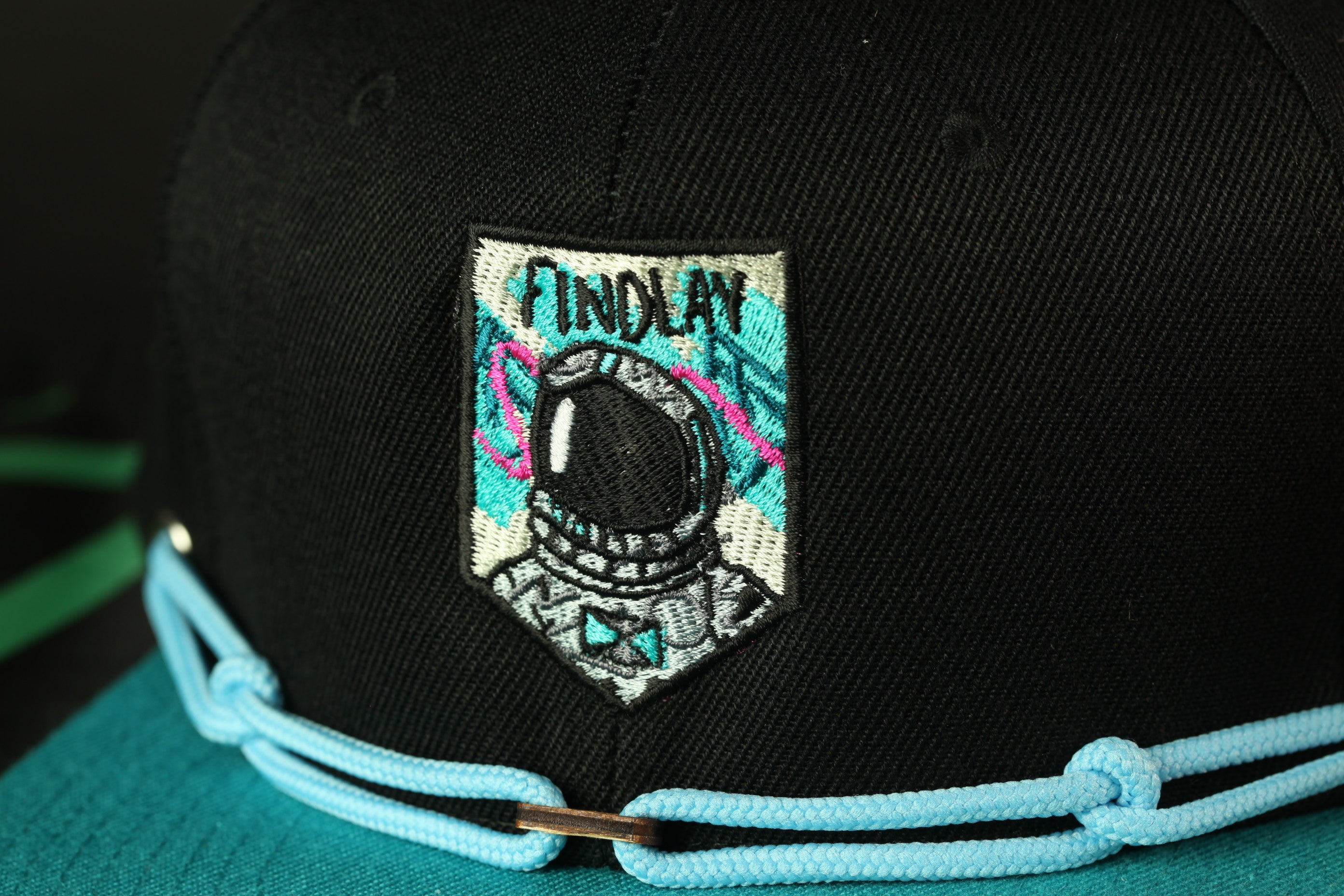 A close-up view of a black baseball cap with a colorful patch featuring an astronaut's helmet and the word "FINDlay" printed on it.