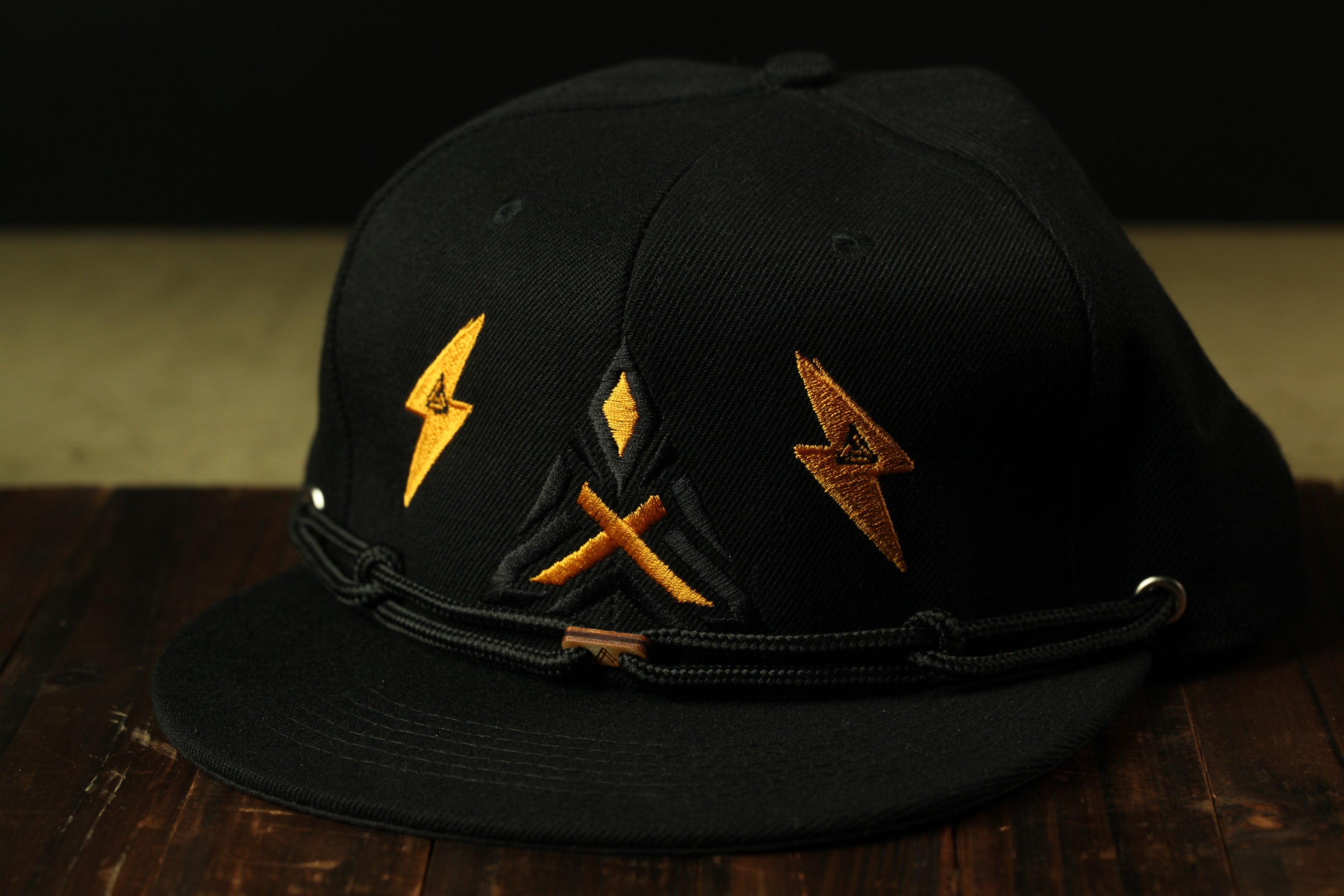 A black baseball cap with yellow lightning bolt designs on the front.