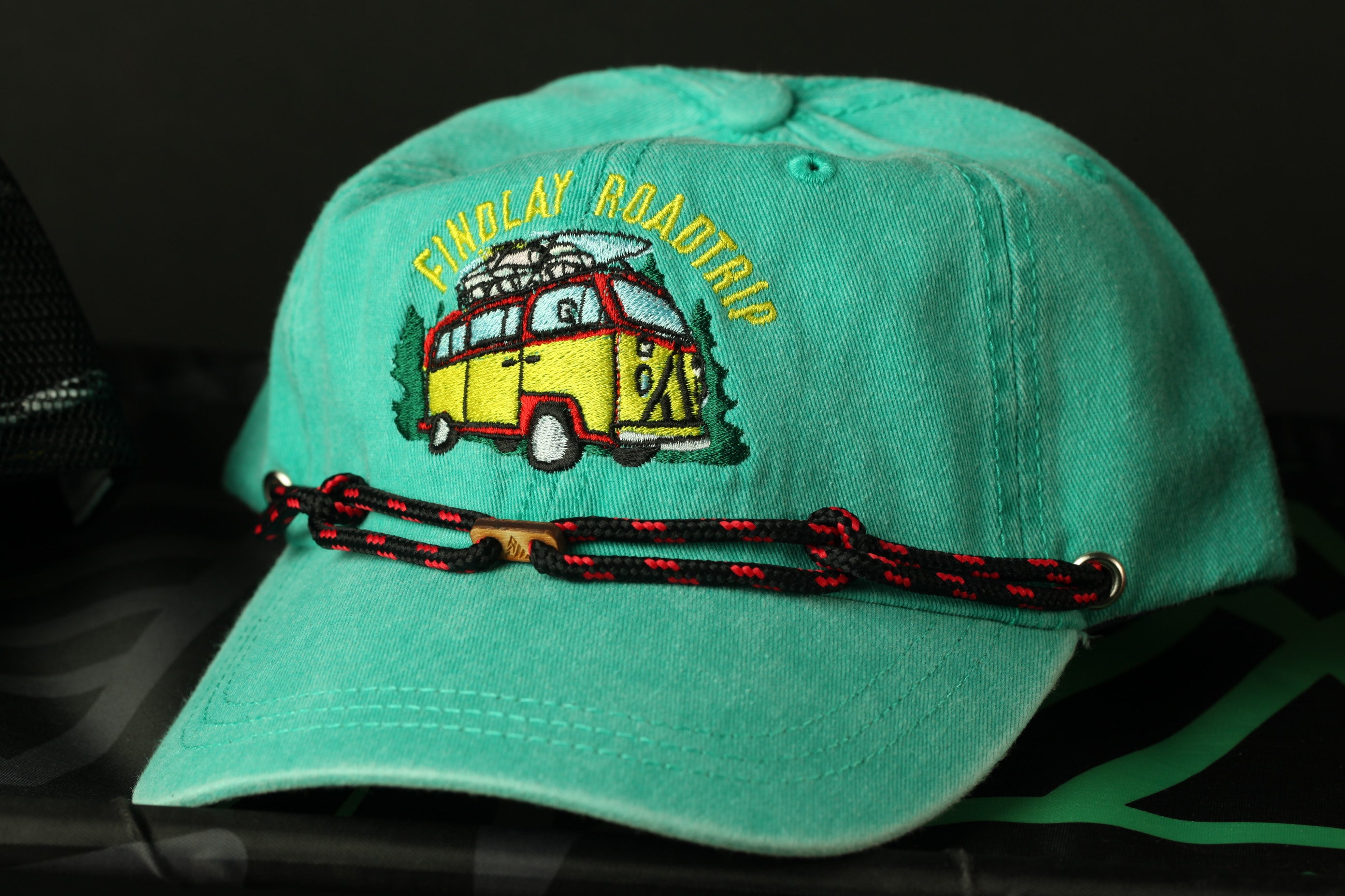 A turquoise baseball cap with a yellow and red van embroidered on it, featuring the text "FINDlay ROADTRIP" on the front.
