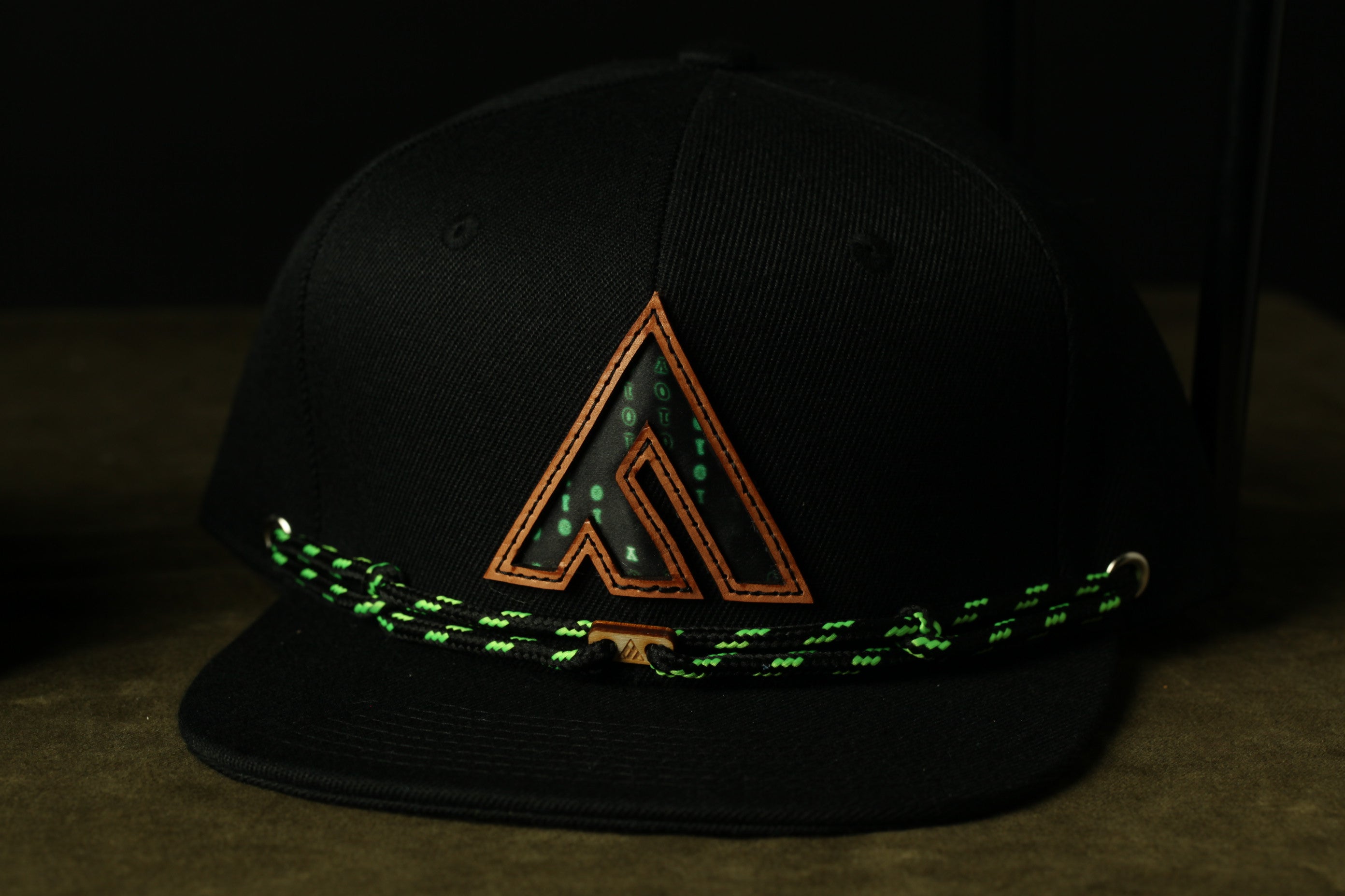 A black baseball cap with a green and orange logo on the front.