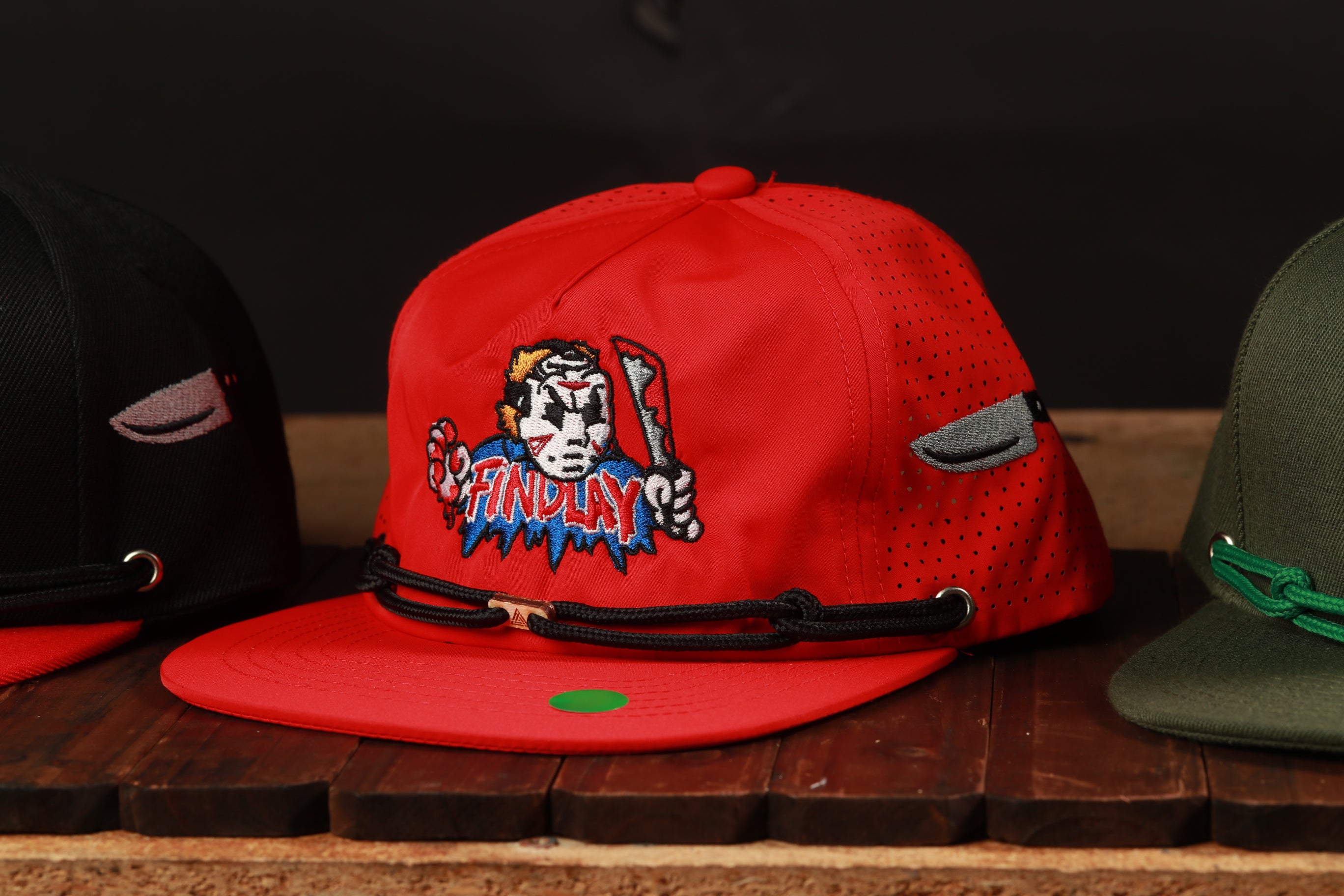 A red baseball cap with a cartoon character on it, sitting on a wooden surface.