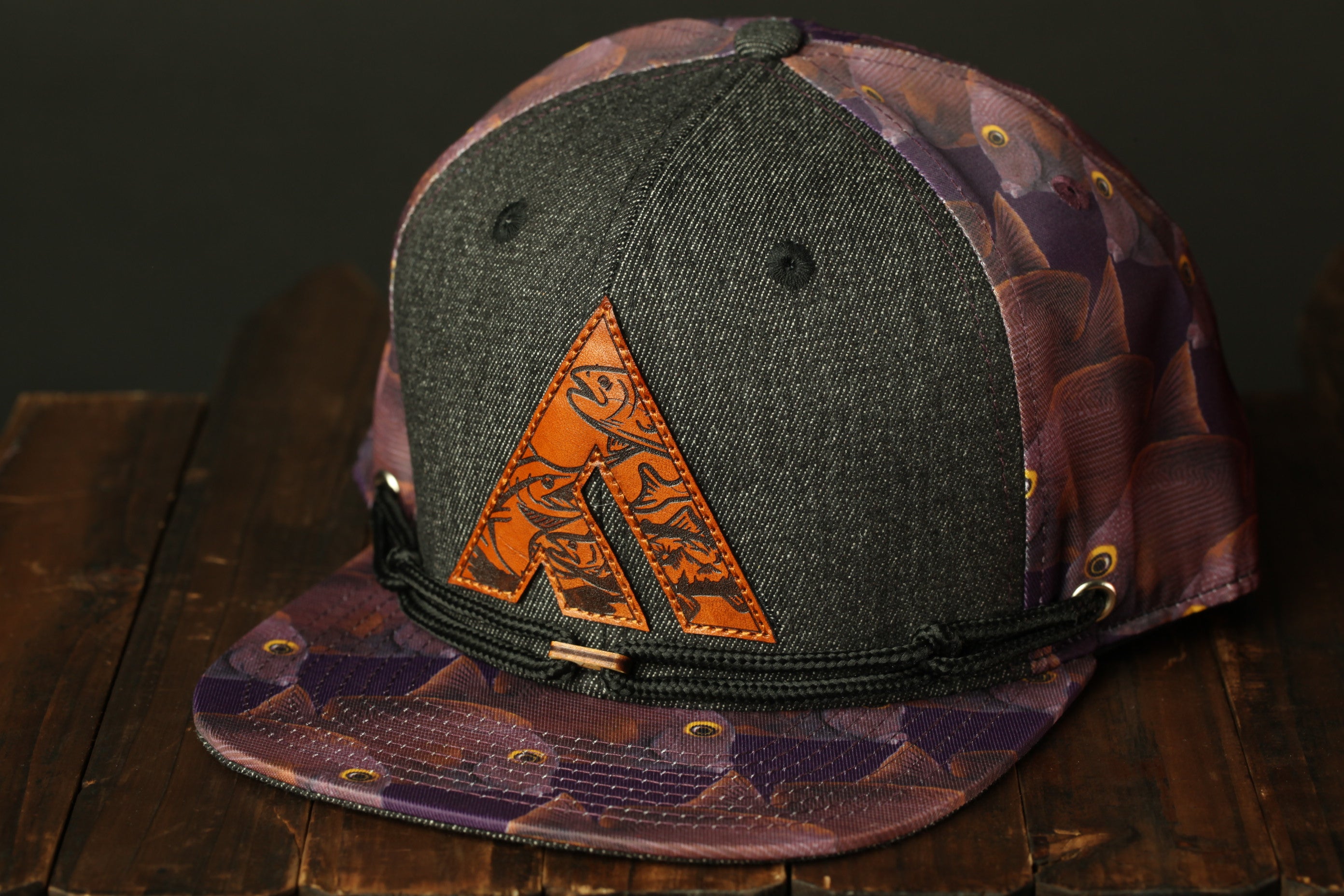 A gray baseball cap with a purple and orange patterned design, featuring a large orange triangle logo on the front.