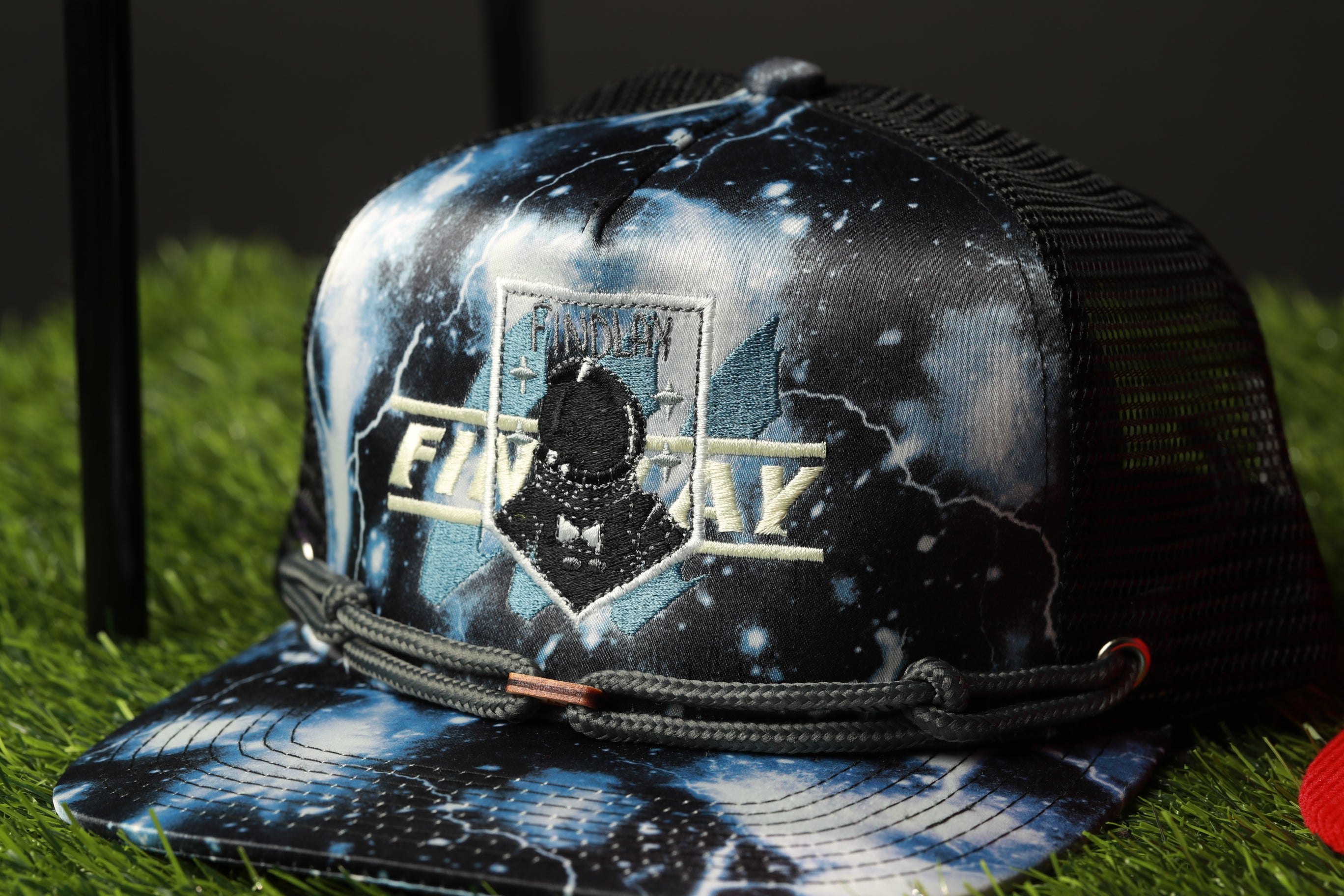A black and blue baseball cap with a mesh back, featuring a patch with the text "FINDEM" and a graphic of a person wearing a helmet.