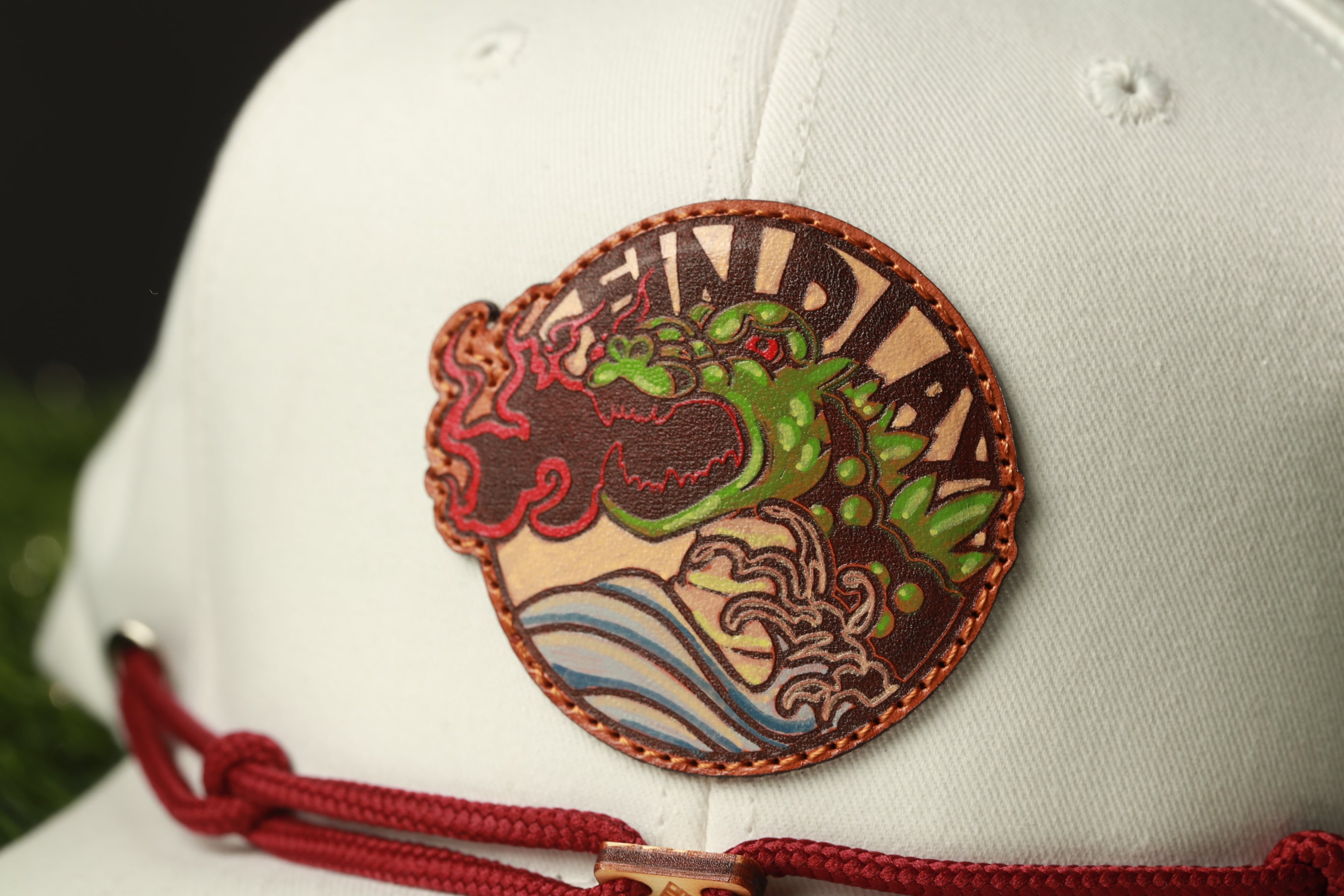 A close-up of a white baseball cap with a circular patch featuring a green dragon design and the word "DUNGEON" written on it.
