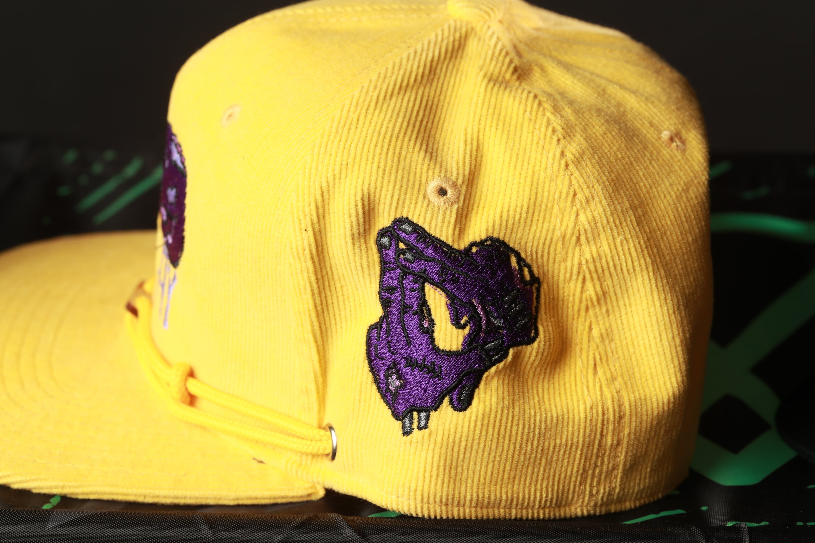 A yellow baseball cap with a purple graphic design on the side.
