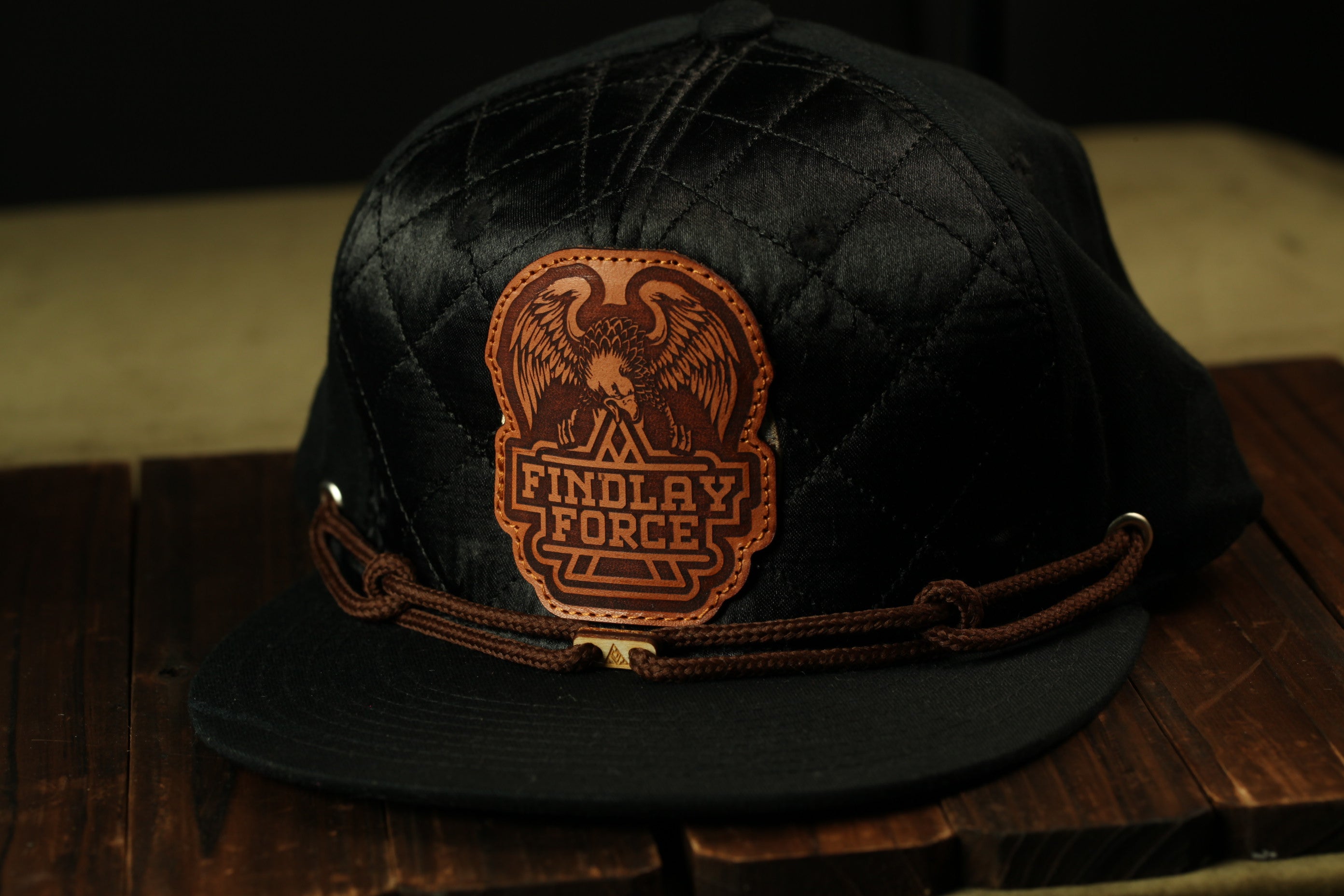A black baseball cap with a leather patch on the front, displaying the text "FINDOLAY FORCE".