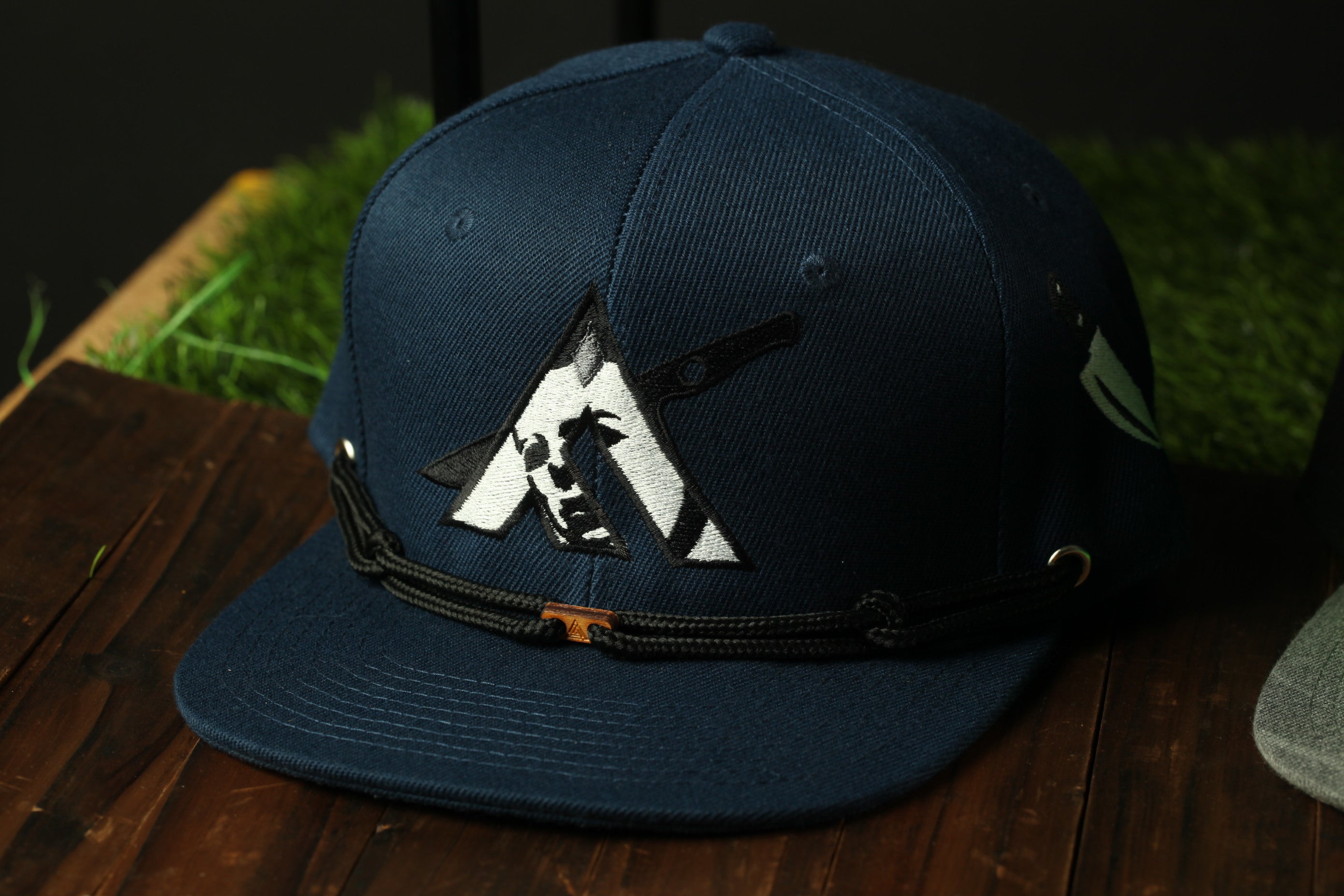 A navy blue baseball cap with a black and white logo on the front, sitting on a wooden surface.