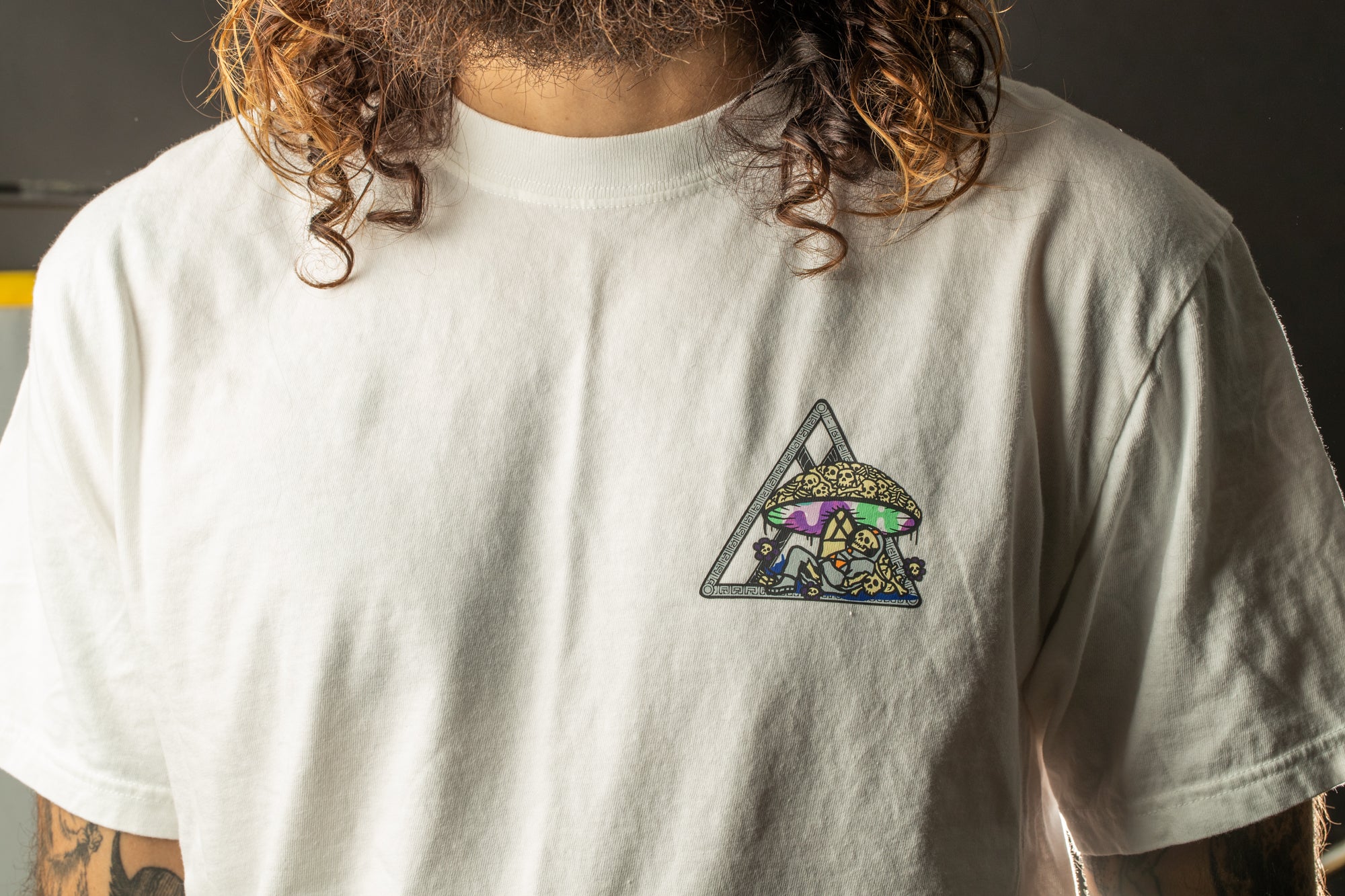 A person wearing a white t-shirt with a colorful triangle design on the front.