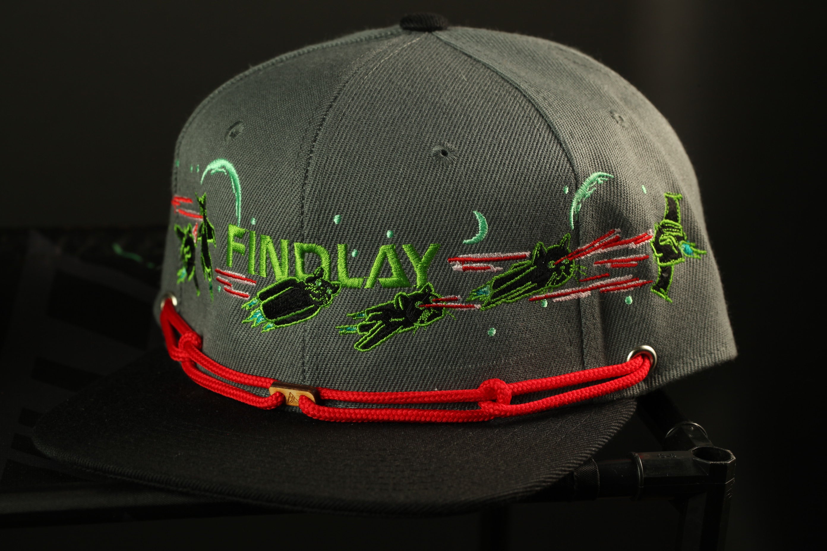 A gray baseball cap with a red string and the word "FINDlay" printed on it.