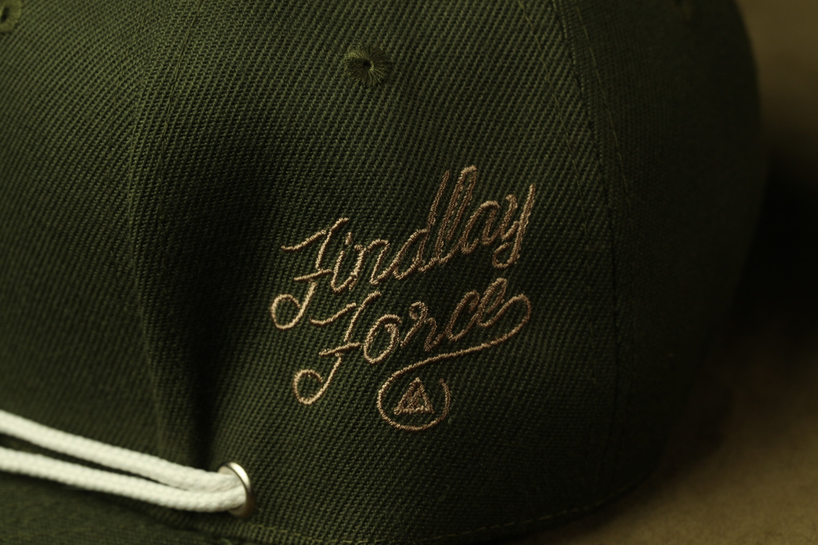 A close-up view of a dark green baseball cap with the embroidered text "Findlay Force" on it.