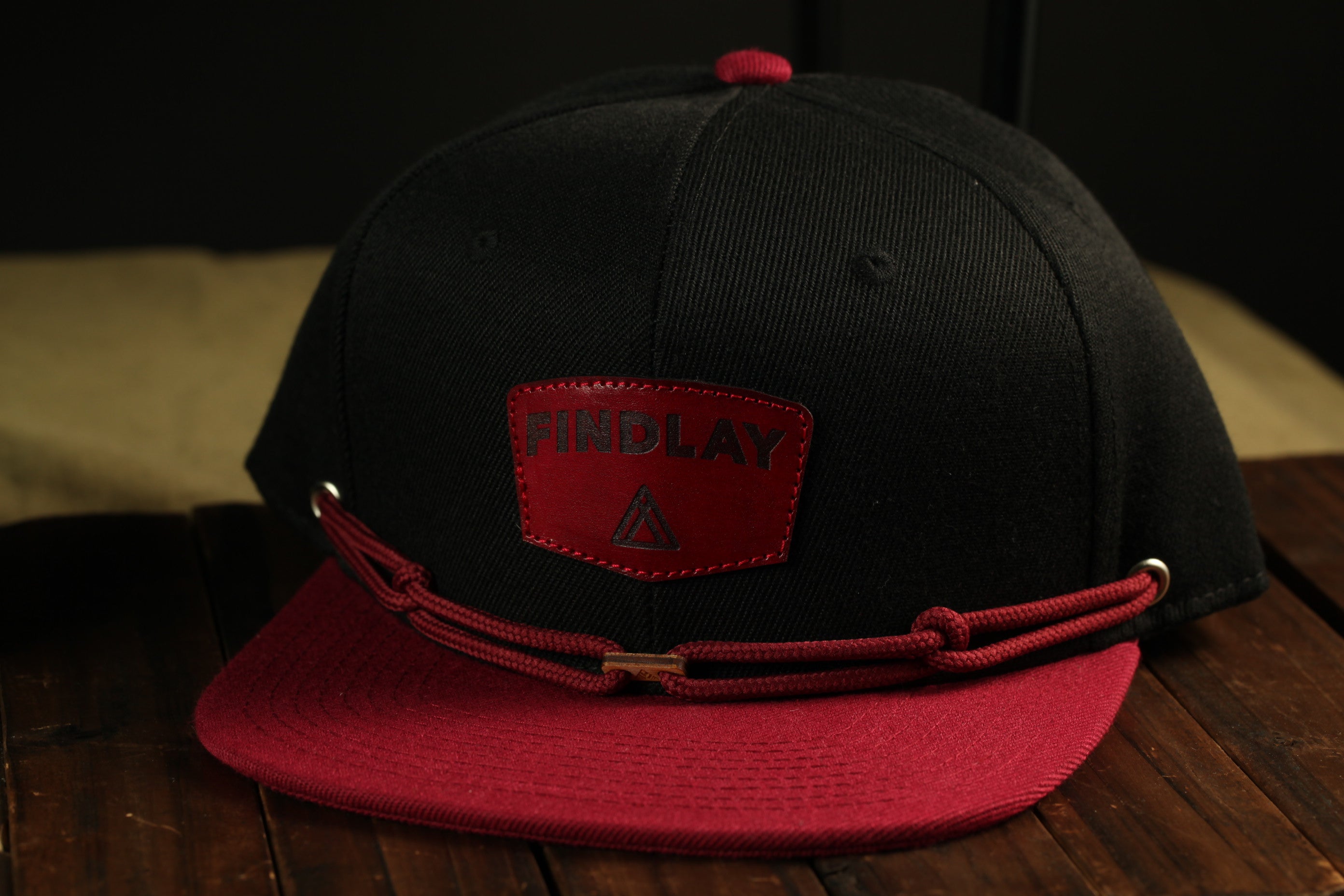 A black baseball cap with a red brim and a red patch on the front displaying the word "FINDlay".