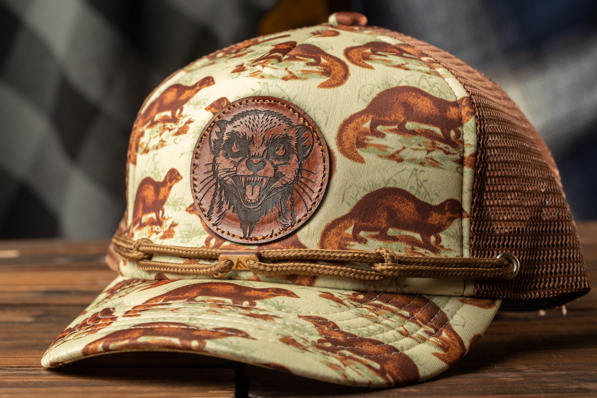 A beige baseball cap with a brown animal print pattern and a brown leather patch featuring a cartoon animal face.
