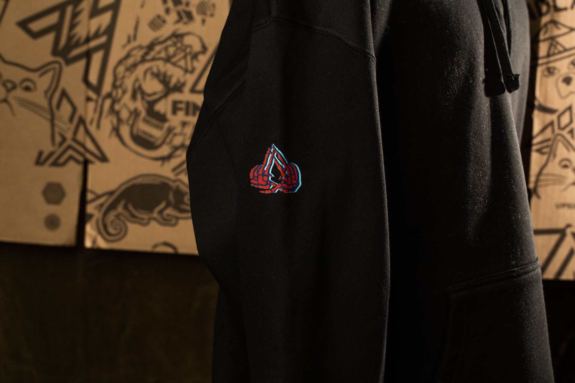 a close-up view of a black hoodie with a colorful logo on the left side.