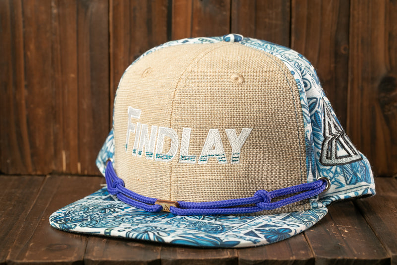 A beige baseball cap with a blue and white floral pattern, featuring the word "Findlay" printed on it.