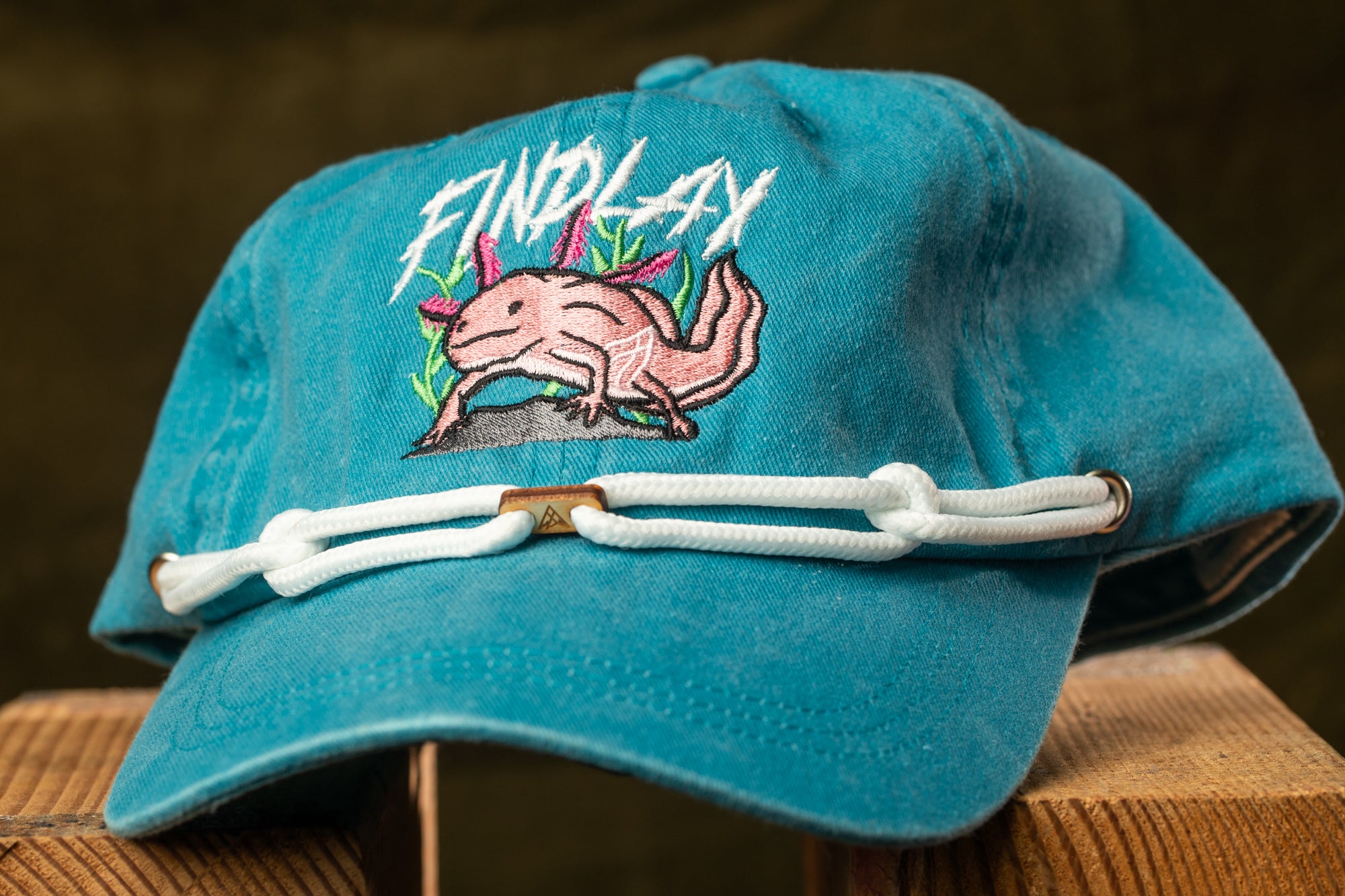 A blue baseball cap with a pink alligator design and the text "FIND LAY" printed on it.