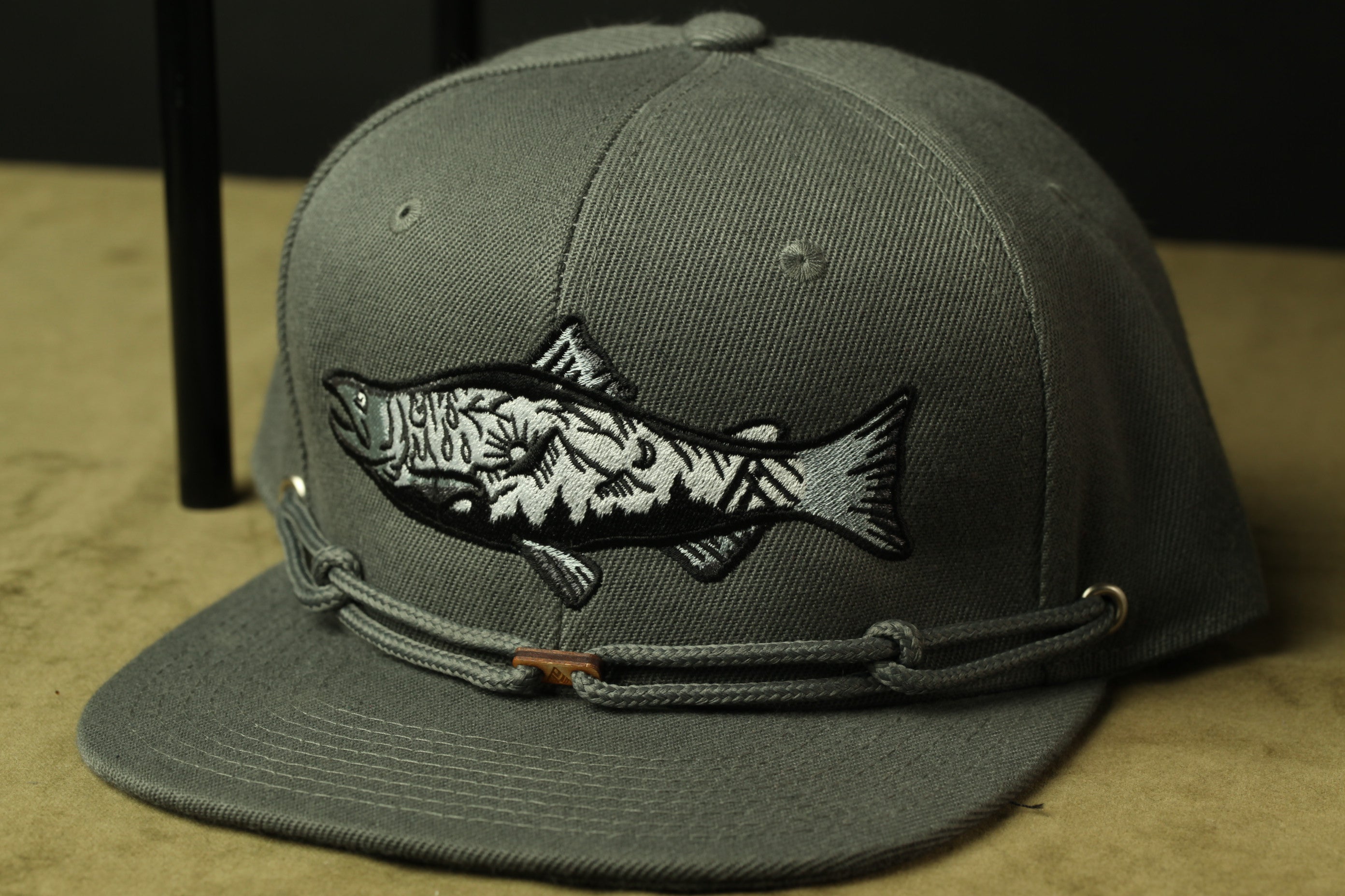 A gray baseball cap with a fish embroidered on the front.