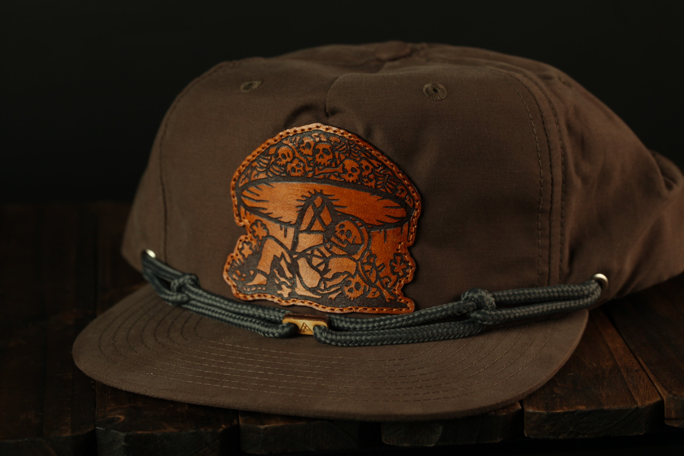 A brown baseball cap with a leather patch featuring an intricate design.