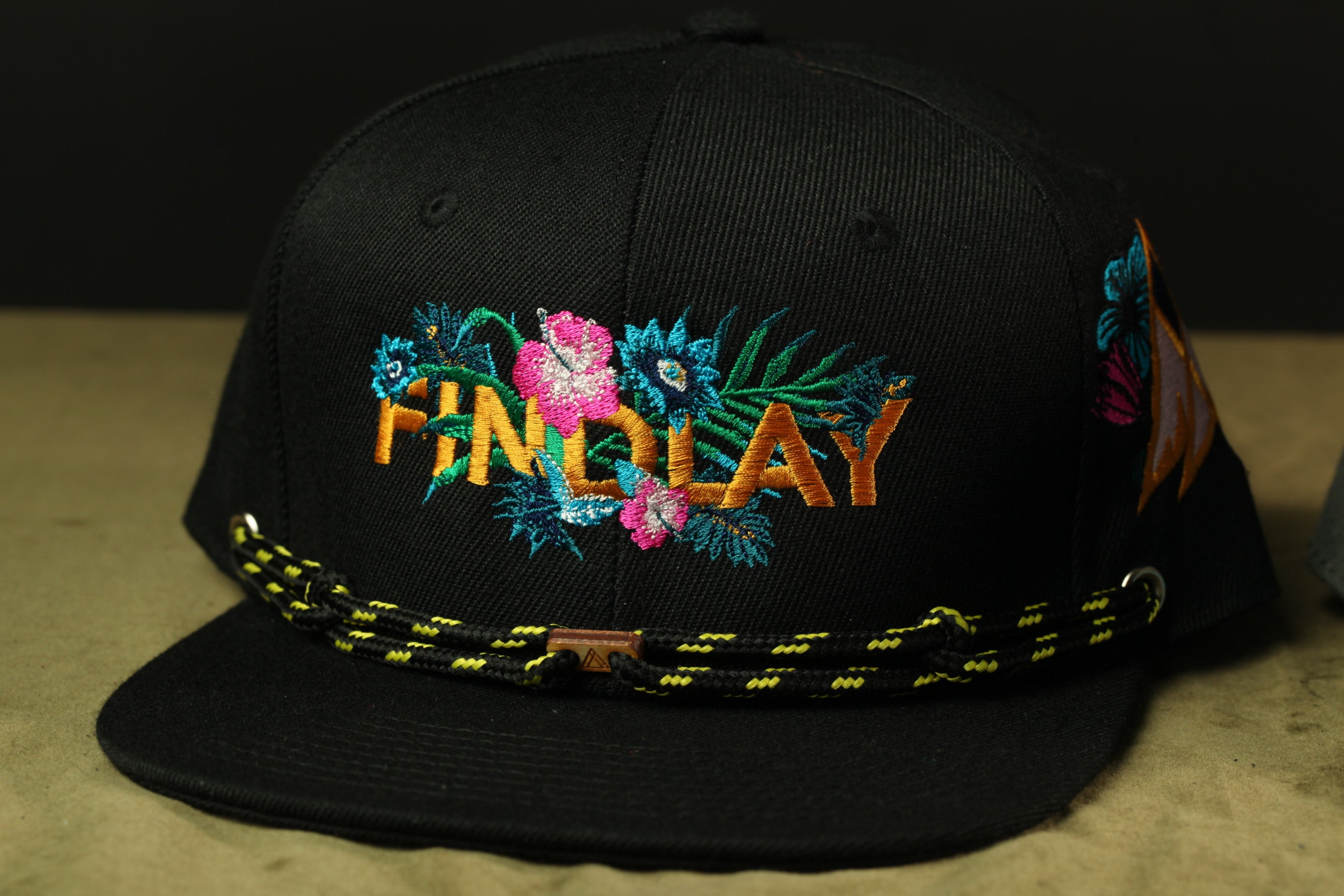 A black baseball cap with a colorful floral embroidered design on the front.