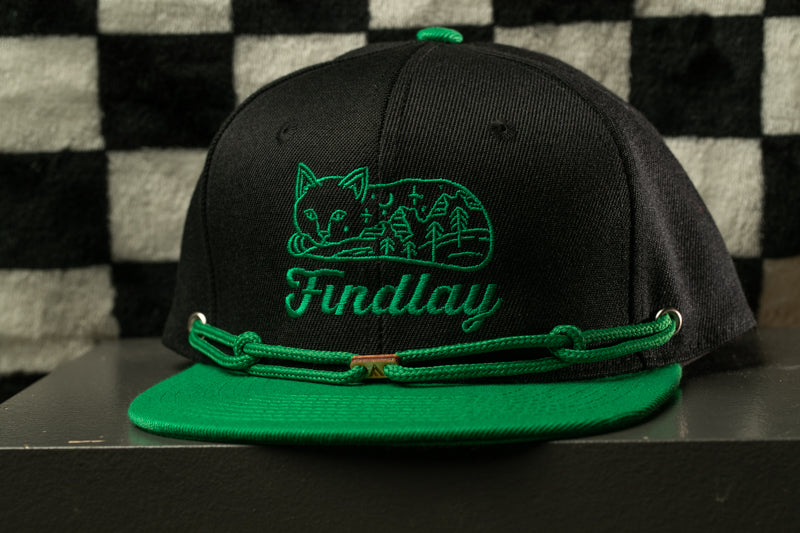 A black baseball cap with a green brim and a green band around the brim, featuring a green embroidered cat logo and the word "Findlay" on the front.