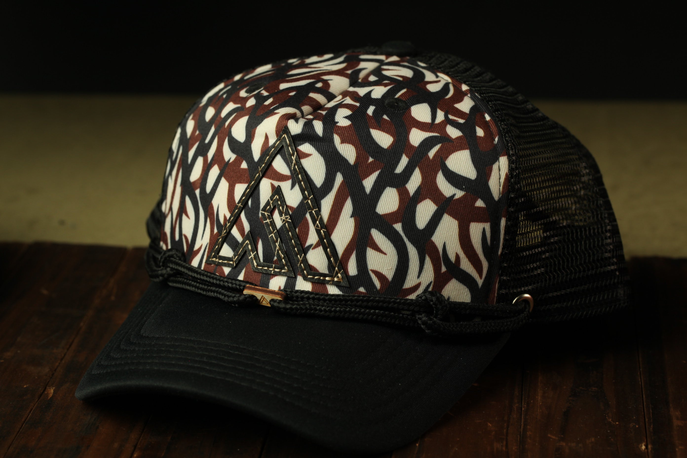 A black and white patterned baseball cap with a mesh back, resting on a wooden surface.
