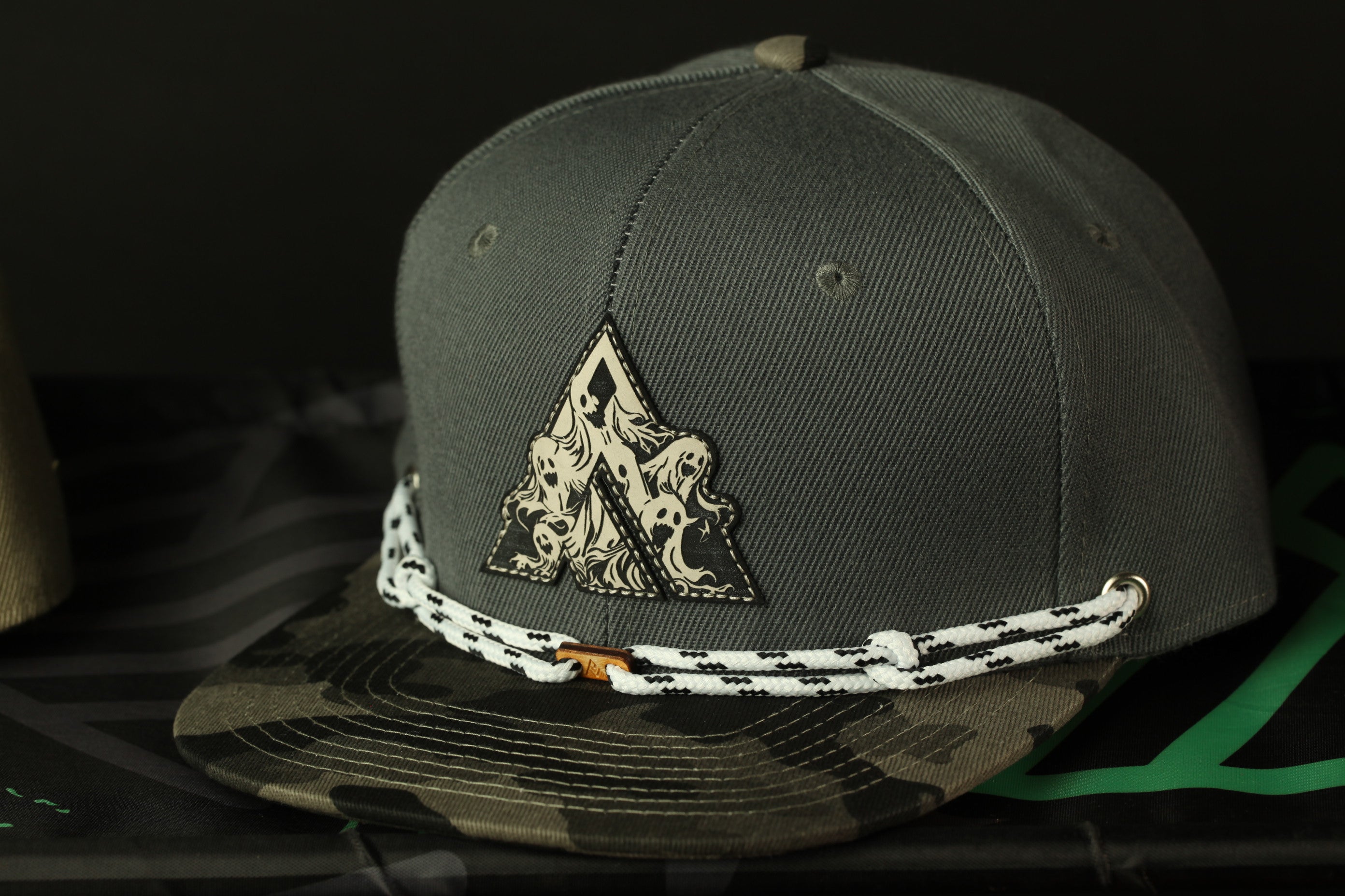 A gray baseball cap with a camouflage pattern and a decorative triangle patch on the front.