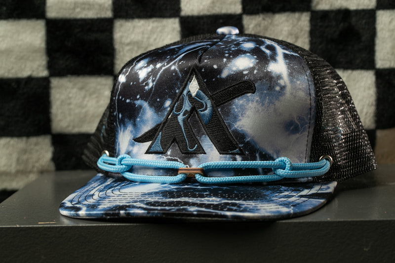 A black and white checkered background with a black and white patterned baseball cap featuring a blue and white design with a black logo on the front.
