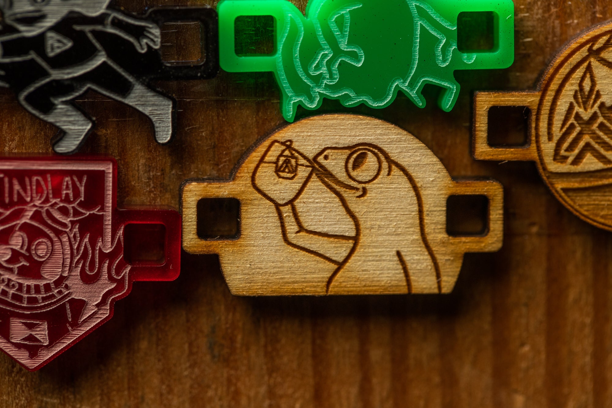 a wooden object with a carved design, surrounded by various other objects, including a red object with a skull and crossbones symbol, a green object resembling a frog, and a brown object with a skull and crossbones symbol.