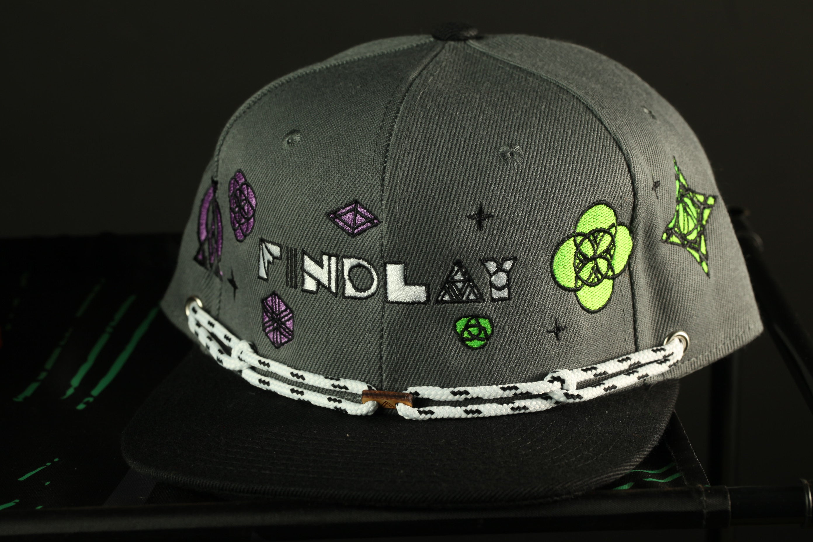A gray baseball cap with various colorful designs and text on it.