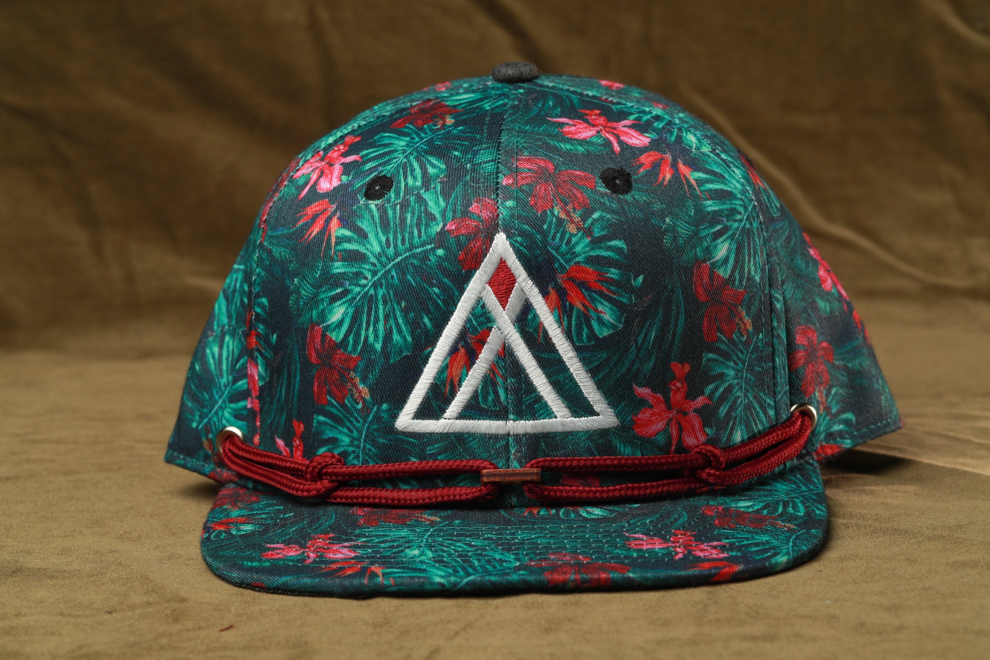 A green baseball cap with a floral pattern and a white triangle logo on the front.